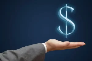 Imagem de uma mão segurando um símbolo de cifrão, o representando impacto da taxa de juros nas decisões do dia a dia.
